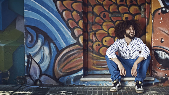 man posing by graffiti wall