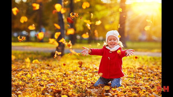 A child playing with fallen leaves in autumn