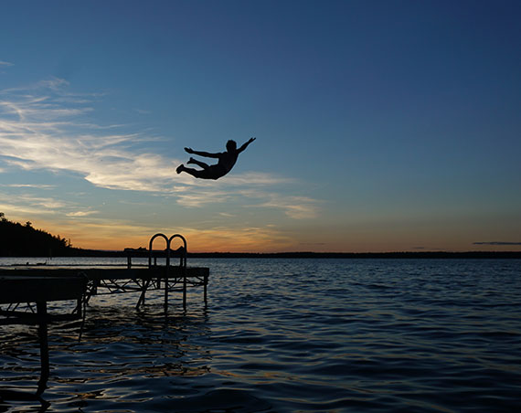 silhouette photo person diving into lake